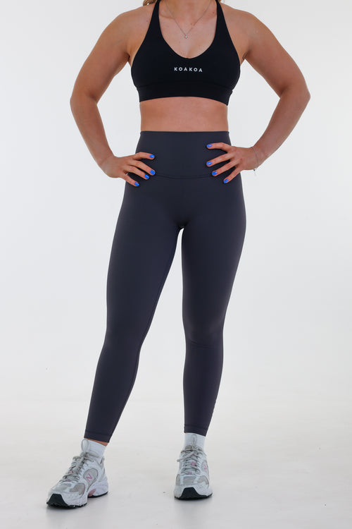 Model wearing Base Leggings in graphite grey, high-waisted with seamless waistband and light compression fit.